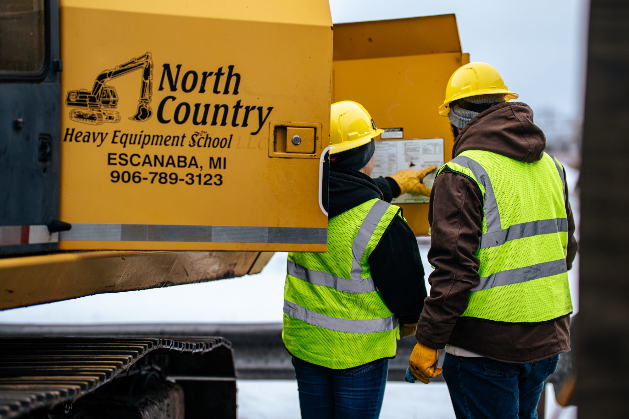 John Deere motor grader operating on a snowy training course at North Country Heavy Equipment School